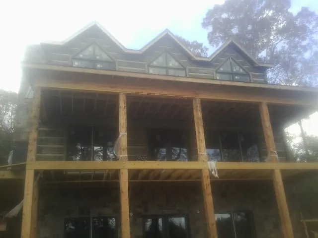 Dormers and porch framing on a large log home under construction — Roof Coating work by our crew in Moro