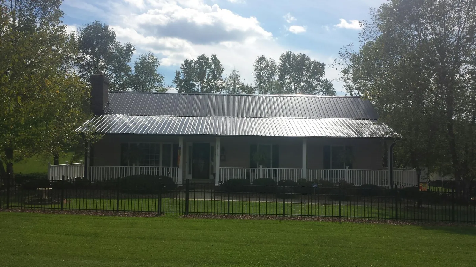 Gray metal roof on a brick ranch with a full width front porch — Gutter Guard Installation work by our crew in Moro