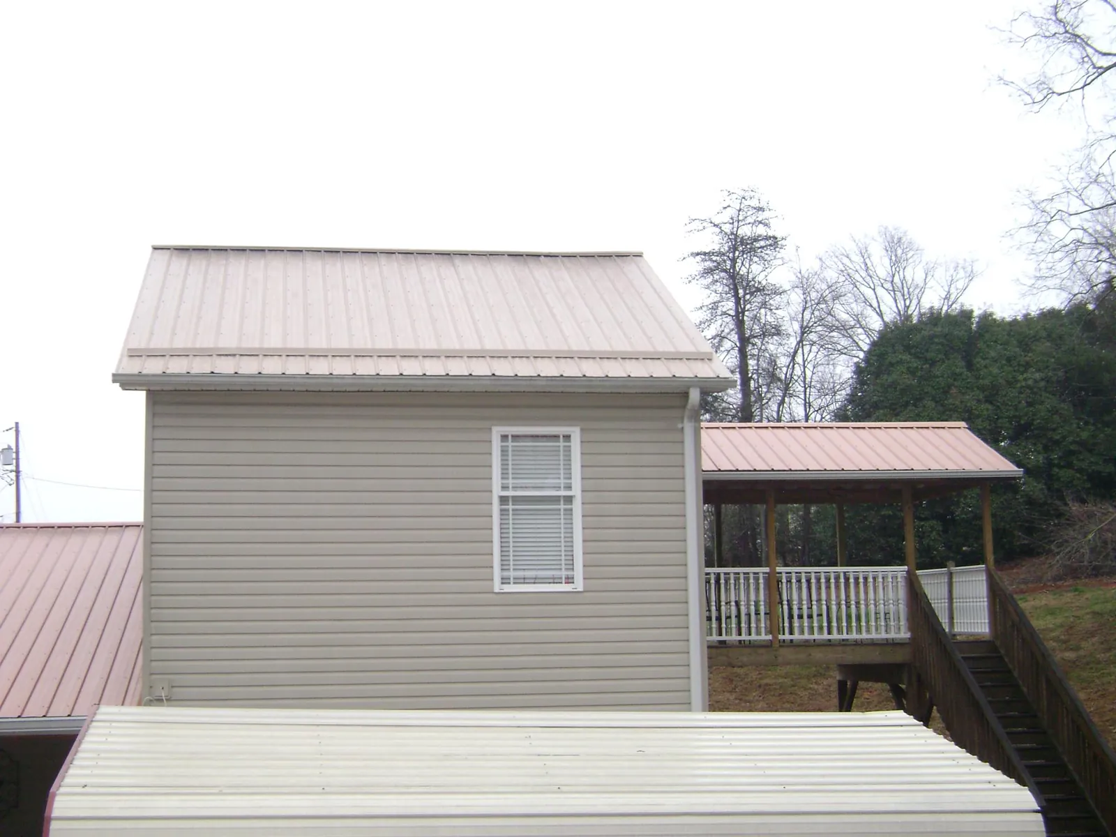 Tan metal roofs on a two story addition and attached porch, from a Roof Replacement job in Moro