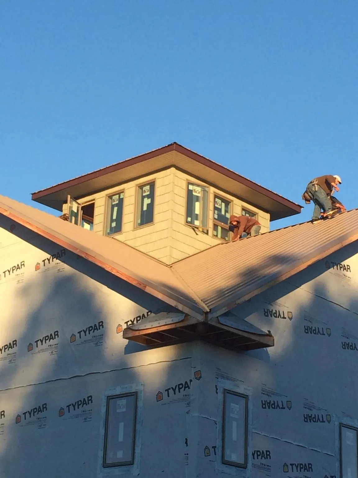 Roofers working around a rooftop cupola on a new metal roof at sunset — Roof Waterproofing in Moro by Roofing Brothers